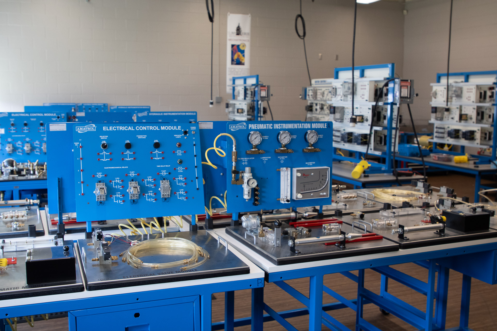 A mechanical engineering technology lab features hands-on training equipment for electrical controls and pneumatic instrumentation, with multiple workstations and industrial training modules.