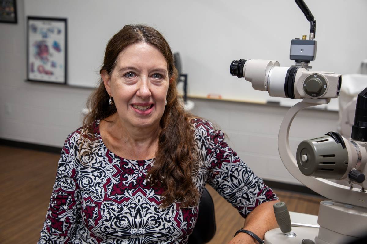 Professor Janet Acara sitting next to an optometry device